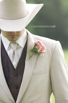 a man in a white suit and tie with a flower on his lapel