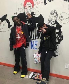 two young men standing in front of a graffiti wall