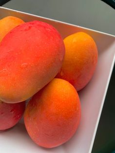 four oranges in a white bowl on a table