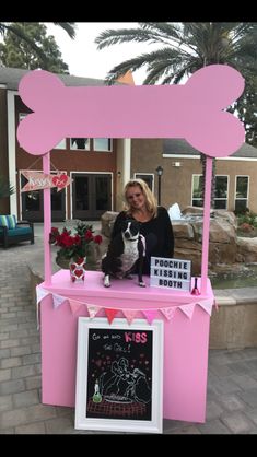 a woman standing behind a pink counter with a dog on it's lap and a chalkboard sign in front of her