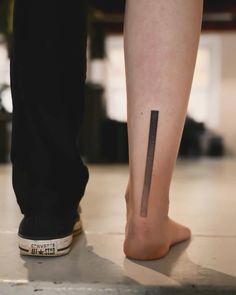 a person's foot with a small tattoo on the side of their leg that has a knife stuck in it