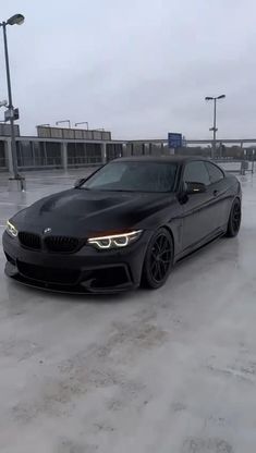 a black car is parked in the middle of a parking lot with no one around it