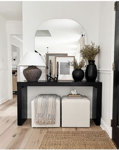 a black and white entryway with two vases on the table, one sitting on a stool