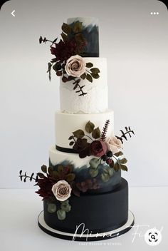 a three tiered cake with flowers and leaves on the top is decorated in white, black, and red