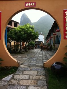 an archway leading into a village with mountains in the background