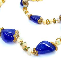 Affinity 20 Karat Yellow Gold Necklace Set with Tanzanite Beads, Opal Beads, and Diamonds. The Necklace Comes With A Lobster Clasp. All Of Our Items Are Handmade. We Believe in Craftsmanship and Originality. 17.39cts diamonds 42.93cts opal 306.97cts tanzanite 20K yellow gold Length: 32 inches The Affinity Collection is a myriad patchwork of cultures, each woven together by a natural attraction to the vibrant, mysterious, and beautiful force emanating from them. The harmonious combination of tumb Elegant Blue Beaded Necklace With Gemstone Accents, Elegant Blue Beaded Necklaces With Gemstone Accents, Elegant Gold Beaded Necklace With Gemstone Accents, Elegant Gold Faceted Beads, Elegant Gold Polished Beads, Gems, And Cabochons, Elegant Gemstone Beaded Necklace For Celebration, Elegant Beaded Gemstone Necklaces For Celebrations, Handmade Elegant Beads For Festive Occasions, Elegant Gold Gemstone Beads And Cabochons