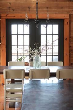 a dining room table with chairs and a vase filled with flowers