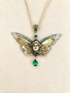 Angel art nouveau necklace, butterfly fairy in old gold brass and green crystal, transparent wings, face necklace: this superb original necklace consists of two pairs of fairy wings, transparent butterfly wings, slightly glittery and tinged with green. In the center, is fixed a plate in old gold brass, art nouveau style, representing a goddess or fairy face with butterfly wings. Under the fairy hangs a drop of emerald green Swarovski crystal, set old gold. The necklace is connected, by an emeral Nickel-free Sterling Silver Fantasy Jewelry, Hand Cast Silver Victorian Jewelry, Fantasy Bronze Metal Jewelry, Silver Fantasy Dangle Jewelry, Face With Butterfly, Fairy With Butterfly Wings, Art Nouveau Angel, Green Fairy Wings, Fairy Lady