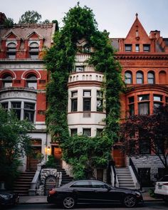 an old building with ivy growing on it's side and cars parked in front