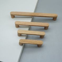 three wooden handles on the side of a white wall next to a gray counter top