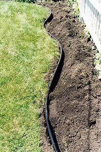 a garden hose in the ground next to a house