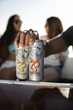 two people are sitting on a boat and one person is holding up a can of beer