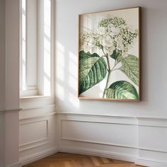 a painting hangs on the wall in an empty room with wood floors and white walls