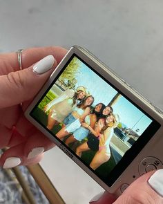 a woman holding up a cell phone with two girls on it's screen in front of her