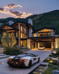 a white sports car parked in front of a large house at night with lights on