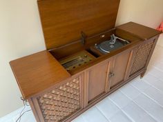 an old fashioned record player in a wooden cabinet with its doors open on the floor