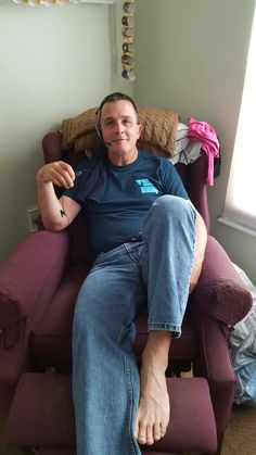 a man sitting in a chair with headphones on his ears and wearing blue jeans