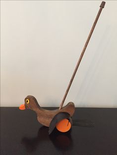 a wooden toy duck pulling an orange ball