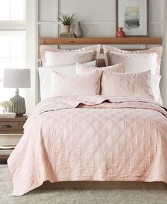 a bed with pink comforter and pillows in a bedroom