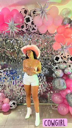 a woman wearing white shorts and a pink hat standing in front of balloons