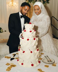 a bride and groom are cutting their wedding cake with cherry decorations on the table in front of them