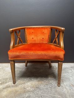 an old wooden chair with orange velvet upholstered on the back and armrests