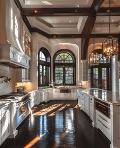 a large kitchen with lots of white cabinets and black counter tops, along with an arched window