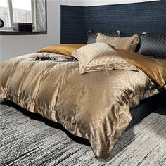 a bed with gold and black comforters in a bedroom next to a large window