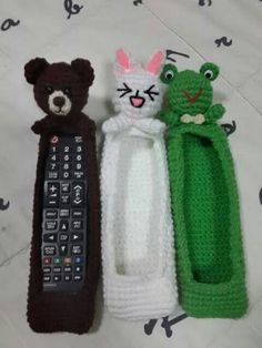 three crocheted stuffed animals sitting next to a remote control on top of a bed