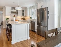 a large kitchen with white cabinets and stainless steel appliances, along with hardwood flooring