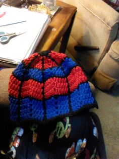 a crocheted hat sitting on top of a chair next to a table with scissors