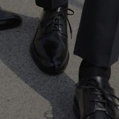 a man in black dress shoes standing on the ground