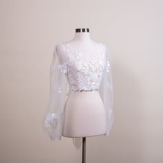 "Romantic puff sleeve lace topper | light ivory bridal lace topper | bridal lace jacket | bridal separates Light ivory wedding dress topper with built in tulle sash at the back. The color is light ivory. It is fully lined with soft tulle fabric. It features satin wrapped buttons at the back. Please note this item is made to order and the lead time is 4 to 5 weeks. We have small, medium, large and x-large sizes available. Size XXL can be made to order but please note that XXL size is not returnable or exchangeable Size Small: Shoulder width: 14.5\" Upper arm circumference: 11.5\" Bust: 34\" US size: 0 ~ 4 UK size: 2 ~ 6 Size Medium: Shoulder width: 15\" Upper arm circumference: 12.5\" Bust: 35.5\" US size: 6 ~ 8 UK size: 8 ~ 10 Size Large: Shoulder width: 16\" Upper arm circumference: 13.5\ Delicate Lace Top For Wedding Night, White Fitted Lace Top With Lace Sleeves, Wedding Lace Top With Sleeves For Spring, Spring Wedding Lace With Lace Sleeves, Fitted Scalloped Lace Tulle, Fitted Lace With Lace Trim For Bride, Fitted White Delicate Lace Top, White Fitted Lace Top With Delicate Design, Long Sleeve White Lace Top For Wedding