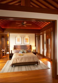 a large bed sitting in the middle of a bedroom next to a wooden ceiling fan