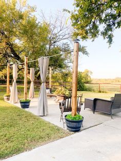 an outdoor patio with chairs, tables and curtains on the side walk in front of it