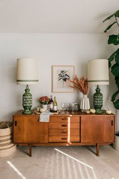 a living room filled with lots of furniture and plants on top of it's sideboard