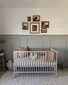 a baby crib in the corner of a room with pictures on the wall above it