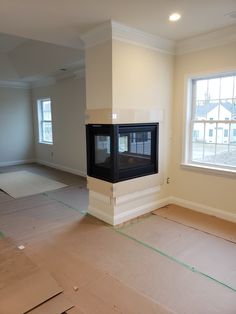 an empty living room with a fireplace in the middle and unfinished flooring on the other side