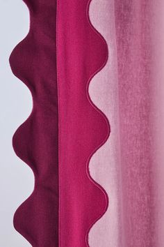 the side of a pink curtain with scalloped edges