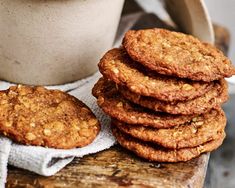 a stack of cookies sitting on top of a wooden cutting board next to a cup