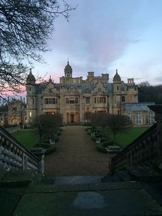 a large building with many windows and lots of trees in front of it at dusk