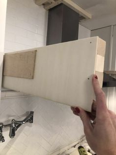 a person is holding up a piece of wood in the kitchen