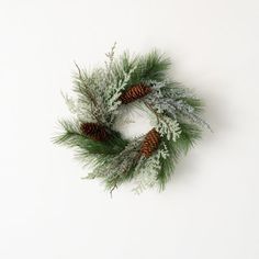 a wreath with pine cones and evergreen needles on a white background, top view from above