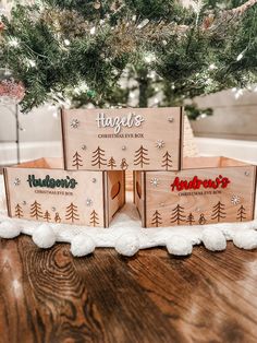 three wooden boxes sitting on top of a table next to a christmas tree with the word happy's written on it