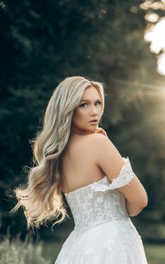 a woman in a wedding dress is posing for the camera with her hair blowing back