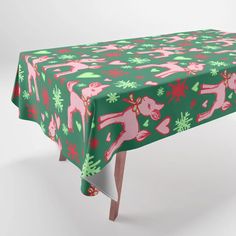 a green and pink christmas tablecloth with reindeers on it's sides, sitting in front of a white background