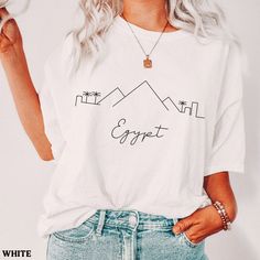 Egypt travel gift for your travels. Picturesque Egypt City Skyline tshirt great as a souvenir. Find warm and cozy Minimal Design sweatshirts, t-shirts, sweaters, and crewneck pullovers with city skylines here. Unisex sweater comes in plus sizes. ABOUT THIS SHIRT  ∙ Shirt is UNISEX and runs slightly large for ladies (For a relaxed fit, I suggest your usual size. For an oversized fit, I suggested is sizing up 1 to 2 sizes.) ∙ 100% Airlume cotton for solid colors, Fabric blends: Heather colors - 52% cotton, 48% polyester; Athletic Heather - 90% cotton, 10% polyester. ∙ Colors may vary based on your monitor or screen display CARE INSTRUCTIONS ∙ Machine wash inside out in cold water ∙ Tumble dry medium or hang to dry ∙ Do not dry clean or iron directly onto the design ESTIMATED PROCESSING & SHI White Crew Neck T-shirt For Travel, White Graphic Print T-shirt For Travel, White Letter Print Top For Travel, Graphic Print Short Sleeve T-shirt For Travel, White Graphic Print Top For Travel, Graphic Tee With Crew Neck For Travel, Egypt City, City Skylines, Egypt Travel