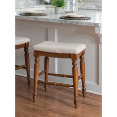 two stools sitting in front of a counter with plates and flowers on top of it