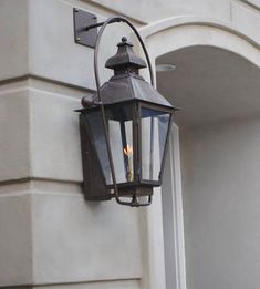 an old - fashioned light is attached to the side of a white building with arched doorways