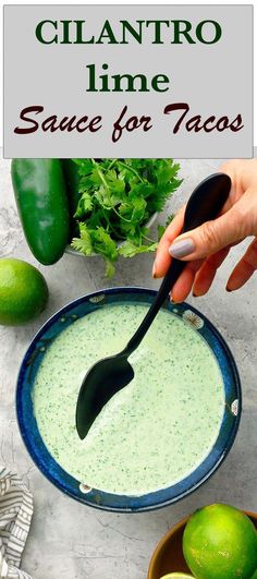 someone is dipping sauce in a bowl with limes and cilantro on the side